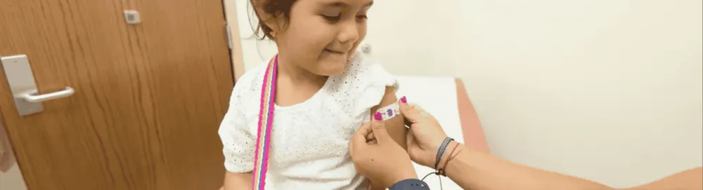 Ein Kind mit einem Pflaster auf dem Arm beim Arzt